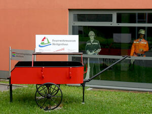 Bild vergrößern: Roter Handwagen mit einem Schild "Feuerwehrmuseum Heiligenhaus".