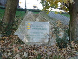 Bild vergrößern: Auf einem an einem Stein befestigtes Schild steht die Aufschrift: "Tierfriedhof Sonnenblume".
