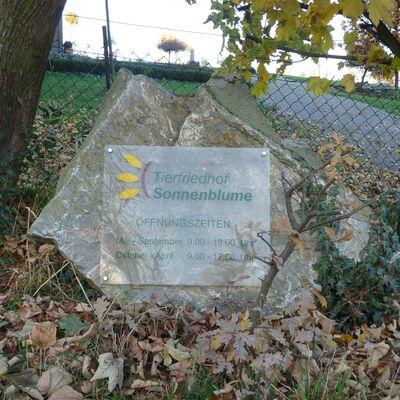 Bild vergrößern: Auf einem an einem Stein befestigtes Schild steht die Aufschrift: "Tierfriedhof Sonnenblume".