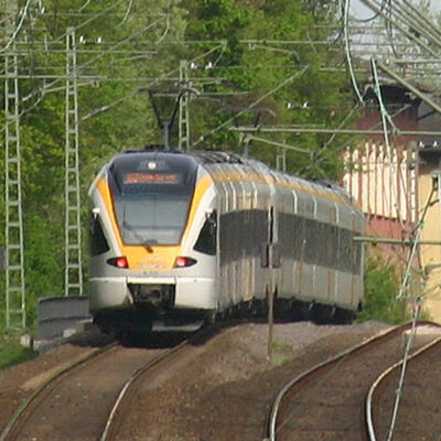 Bild vergrößern: Fahrender Regionalexpress auf einem mehrgleisigen Bahnabschnitt.