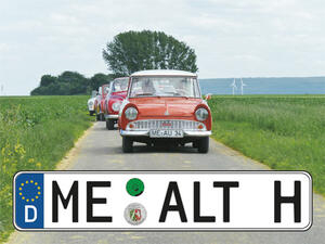 Bild vergrößern: Oldtimer befahren eine Landstraße. Im Vordergrund ein KFZ-Kennzeichen mit den Initialen: "ME ALT H".