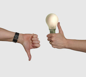 Bild vergrößern: Eine Hand hat den Daumen nach unten gerichtet, eine weitere Hand hat den Daumen nach oben gerichtet und hält eine erleuchtete Glühbirne.