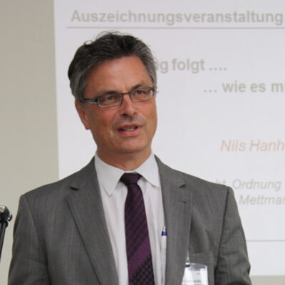 Bild vergrößern: Kreisumweltdezernent Nils Hanheide steht vor einer Leinwand, auf welcher eine Präsentation gezeigt wird mit der Überschrift: "Auszeichnungsveranstaltung".