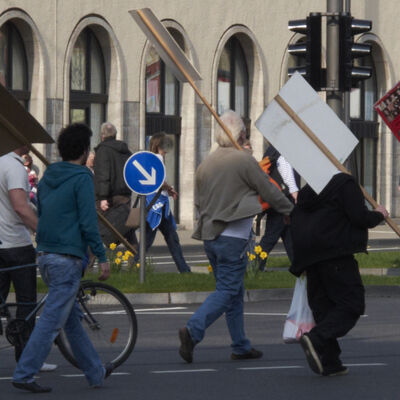 Bild vergrößern: Mehrere Personen mit Schildern in der Hand haltend laufen als Gruppe zusammen.