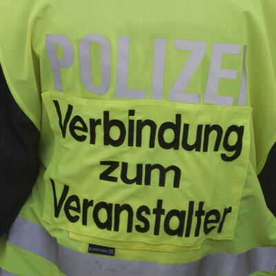 Bild vergrößern: Gelbe Warnjacke mit der Aufschrift "Polizei- Verbindung zum  Veranstalter".
