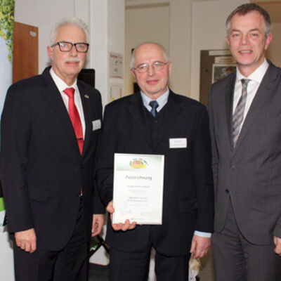 Bild vergrößern: Landrat Thomas Hendele und Minister Johannes Remmel übergeben einer männlichen Person eine Urkunde.