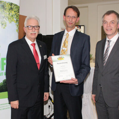 Bild vergrößern: Landrat Thomas Hendele und Minister Johannes Remmel übergeben einer männlichen Person eine Urkunde.