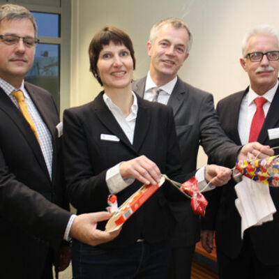 Bild vergrößern: Schulleiter Peter Schwafferts, Bürgermeisterin Birgit Alkenings, Minister Johannes Remmel, Landrat Thomas Hendele halten an einer Schnur miteinander befestigte Verpackungsmaterialien in den Händen.