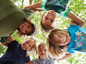 Bild vergrößern: Fünf Kinder stecken ihre Köpfe in der Mitte zusammen.