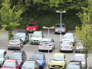 Bild vergrößern: Parkplatz mit zahlreichen Autos und Parklaternen.