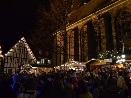 Bild vergrößern: Personen stehen dicht gedrngt an weihnachtlich geschmckten Verkaufsstnden.