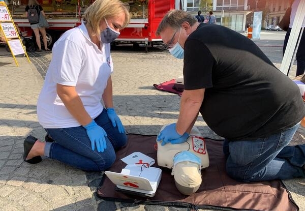 Bild vergrößern: Foto: (v.l) Melanie Dittmann (Deutsches Rotes Kreuz) und Ralf Koch (Bildungsakademie) simulieren auf dem Mettmanner Jubliumsplatz eine Herz-Lungen-Wiederbelebung