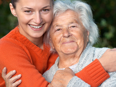 Bild vergrößern: Eine junge Frau hlt eine ltere Dame im Arm.