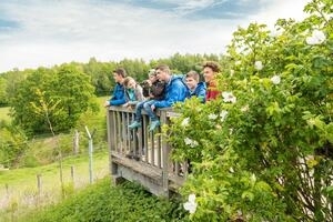 Bild vergrößern: Eine Familie blickt an einem Geländer einer Aussichtsplattform stehend in ein eingezäuntes Gehege hinab.