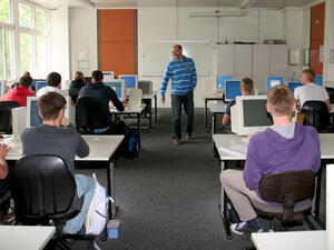 Bild vergrößern: Ein Lehrer steht vor seiner Computerklasse.