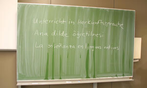 Bild vergrößern: Auf einer Unterrichtstafel steht in verschiedenen Sprachen "Unterricht in Herkunftssprachen".