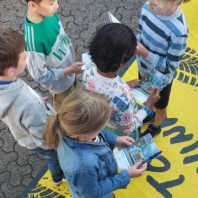 Bild vergrößern: Kinder die ein Quiz zum Thema "Die Gefahren des toten Winkels" in der Hand halten.