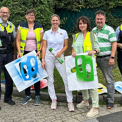 Bild vergrößern: Gruppenbild von einer Aktion bei der Fußspuren als Markierung auf die Straße gesprayt wurden zum Thema "Wir wollen gehen! Zu Fuß statt Elterntaxi".