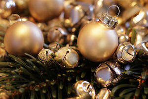 Bild vergrößern: Goldene Weihnachtskugeln und Glckchen in einem Tannenzweig.